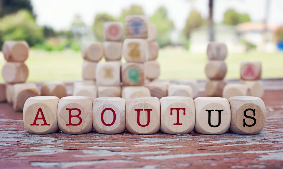 Wooden lettered blocks arranged outdoors to spell the words About Us.