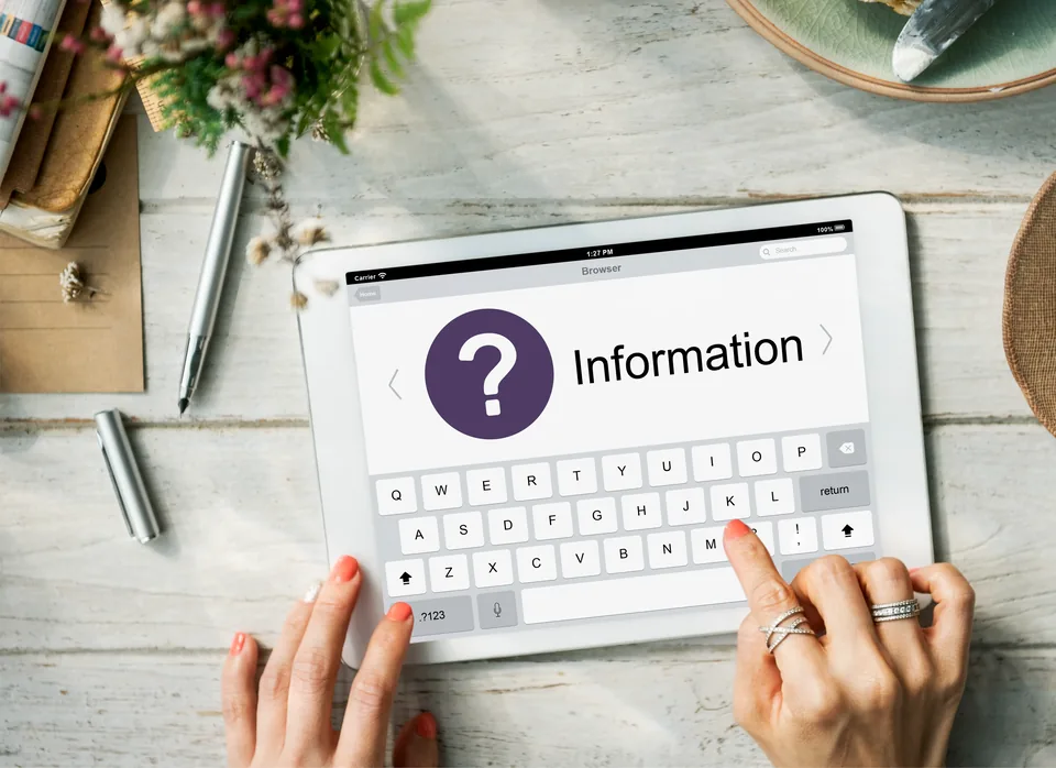 A tablet on a wooden desk displaying an information page with a question mark icon.