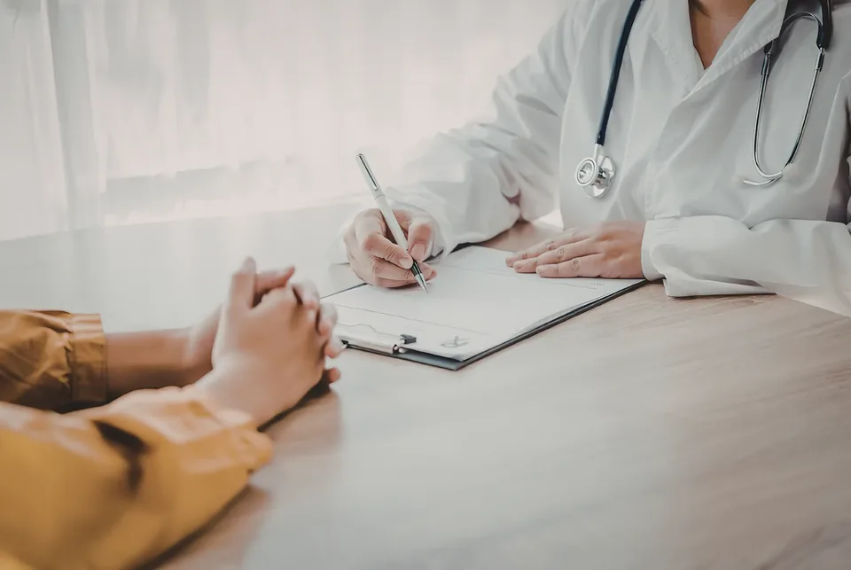 A practitioner making notes at a desk during a consultation, with a client seated opposite.